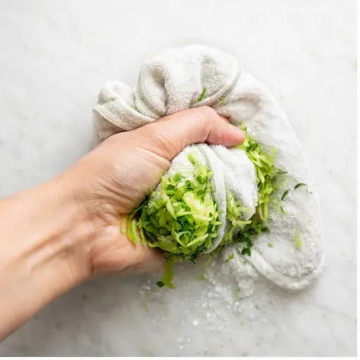 Step 1: Squeezing moisture from grated zucchini