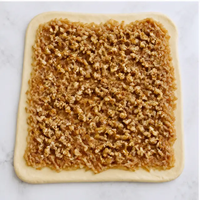 Step 3: Spreading filling over rolled dough with nuts