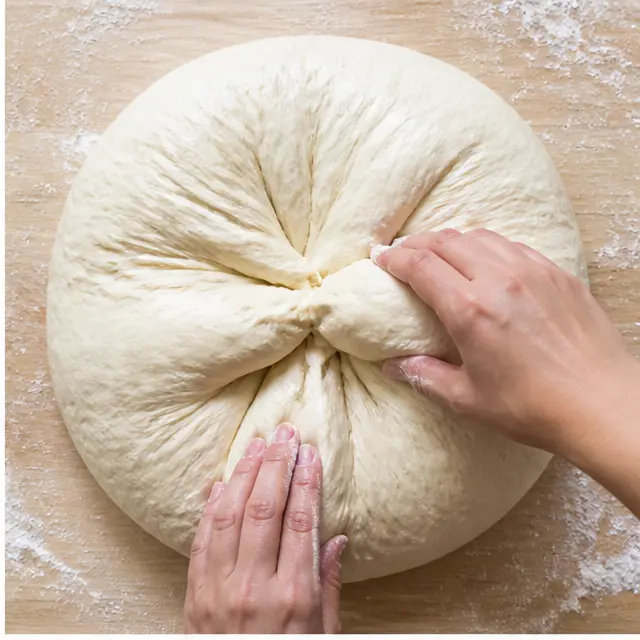 Folding the doubled risen dough into a ball on a floured surface