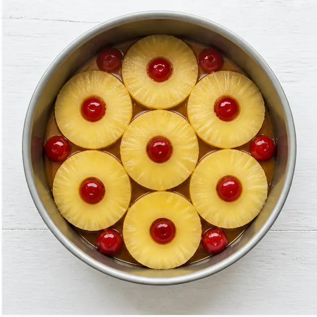 Arranging pineapple rings and cherries in the caramel