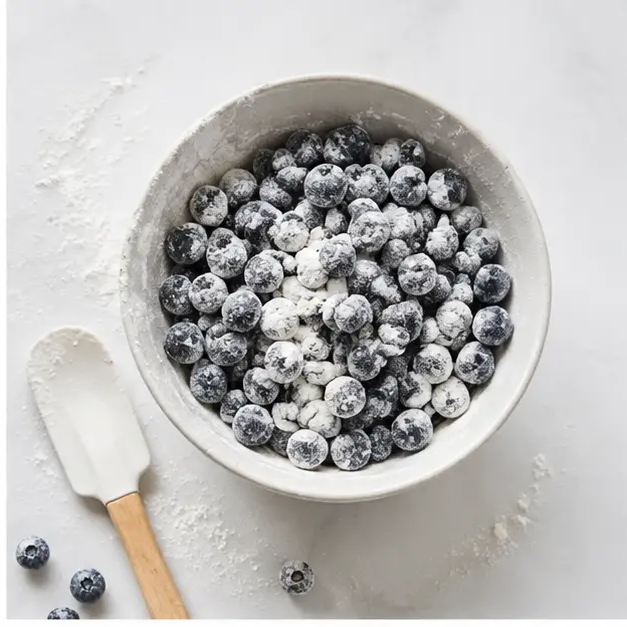 Step 2: Tossing dark purple blueberries in flour to prevent sinking