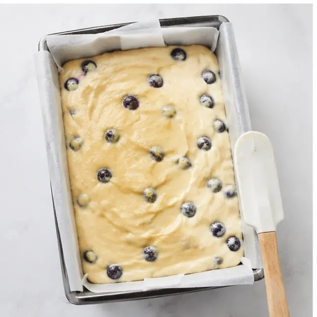 Step 3: Filling the parchment-lined loaf pan with blueberry-studded batter