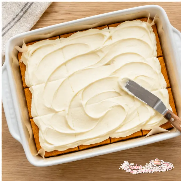 Step 4: Spreading a thick layer of cream cheese frosting with an offset spatula over completely cooled golden-orange pumpkin bars, leaving visible decorative swirls before chilling and slicing